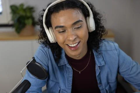 Non-binary person wearing denim shirt recording with microphone and white 写真素材
