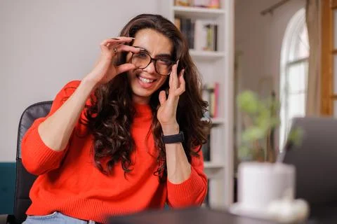 Non-binary person working with a big smile while adjusting their glasses Stock Photos