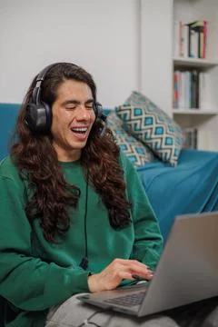 Non-binary person working from home with their laptop and headphones with a.. Stock Photos
