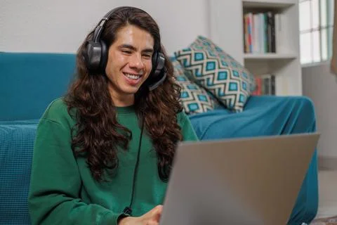 Non-binary person working from home with their laptop and headphones with a.. Stock Photos