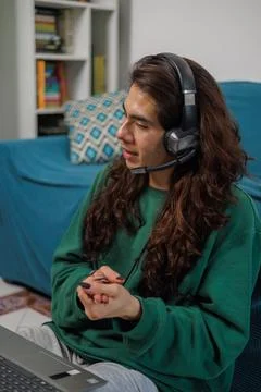 Non-binary person working from home with their laptop and headphones with a.. Stock Photos