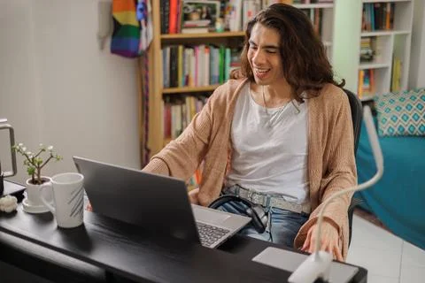 Non-binary person working from home at their desk with their computer and c.. Stock Photos