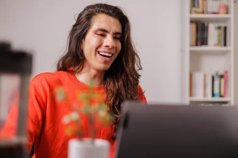 Non-binary person working from home on their laptop with a big smile Stock Photos