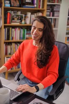 Non-binary person working from home on their laptop with a big smile Stock Photos