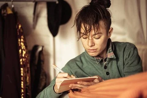 Non-binary person writes in journal at home on cosy warm couch berlin Stock Photos