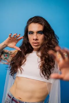 Non-binary stylish person with editorial pose on blue background and copy spa Stock Photos