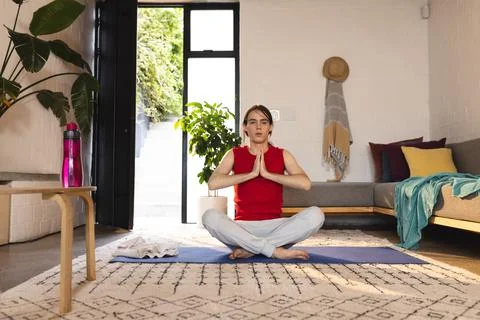 Non-binary trans woman practicing yoga and meditation sitting on yoga mat at Stock Photos