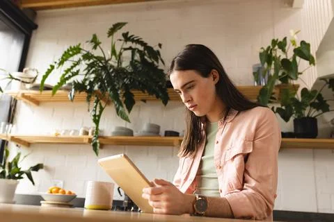Non-binary trans woman using digital tablet in the kitchen at home Stock Photos