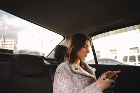 Non-binary woman using smart phone while traveling in car Photos