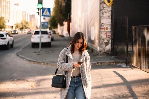 Non-binary woman using smart phone while walking in city Stock Photos