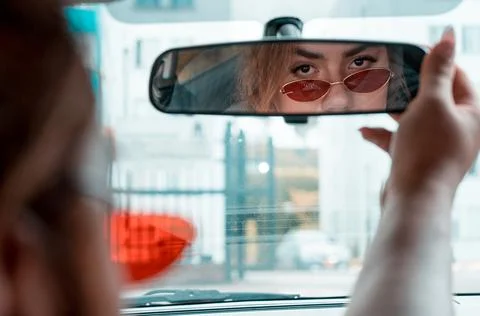Non-binary young driving a car looking in the rear view mirror Stock Photos