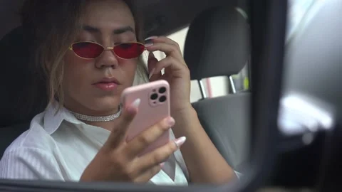 Non-binary young looking your phone at car in the rear view mirror Stock Footage 194863639