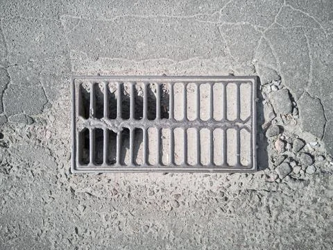 The non-functioning grate of the street stormwater storm sewer Stock Photos