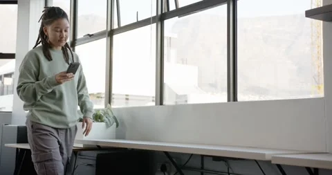 Nonbinary entering office propping leg on bench, sitting, scrolling phone Stock Footage 344693539