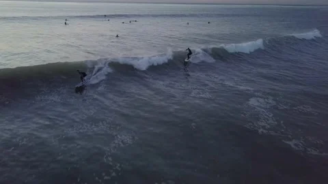 Nondescript surfers riding a wave Stockbeeldmateriaal 221379852