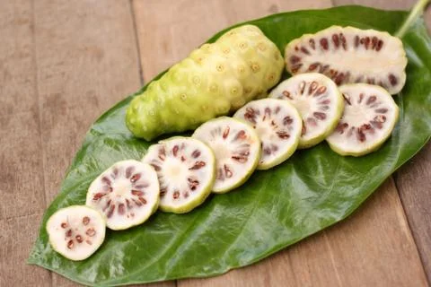 Noni slice on noni leaf on table. Foto stock