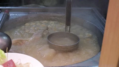 Noodle strainer in large pot with whole chicken boiling at street food market Stock Footage 336442179