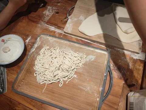 Noodles being made on the kitchen table, with a rectangular wooden board co.. Stock Photos