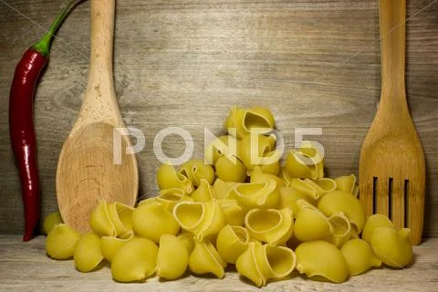 Noodles Seashells And Wooden Spoon On Wooden Background