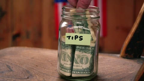 Nop5Putting dollars into a tip jar Видео 277651392