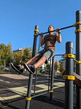 Normal man exercising outside. Holding his upper body above horizontal bar Stock Photos
