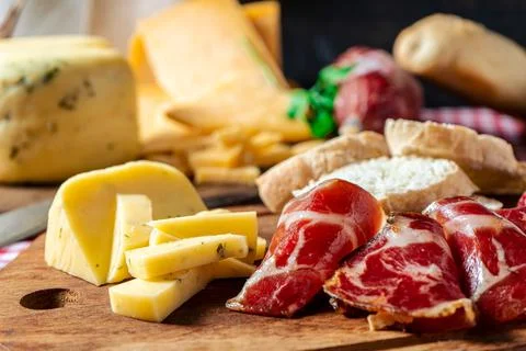 Normal view of a small board of different cheeses with salami, ham and olives Stock Photos