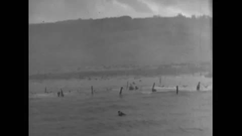 NORMANDY - 1944 - Smoke, barbed wire, and sunken infantry landing craft are on Stock Footage 312792882