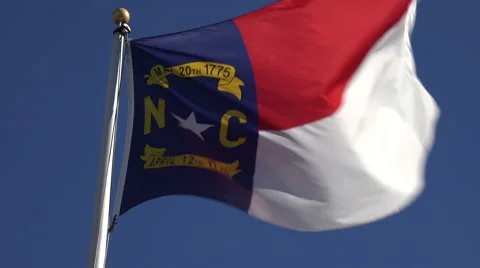North carolina flag in wind with blue sky background, nc, usa Stock Footage 45452359