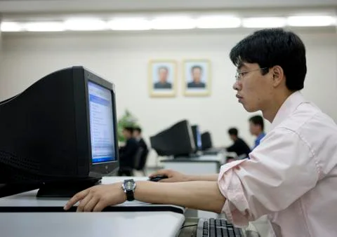 North Korean man using a computer under the Dear Leaders pictures in the Gran Stock Photos