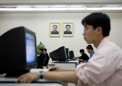 North Korean man using a computer under the Dear Leaders pictures in the Gran 스톡 사진