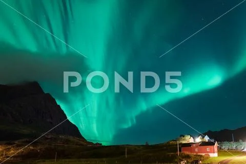 Northern lights Aurora Borealis over illuminated fishing village of reine Stock Photos