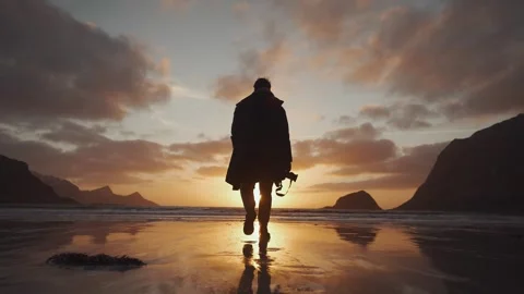 Norway sunset beach man walking holding a camera Stockbeeldmateriaal 304580993