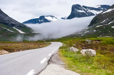 Norwegian asphalt road with hovering cloud between the mountains Stock Photos