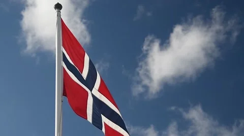 A Norwegian flag flutters in the wind against a blue sky background Stock Footage 65730829