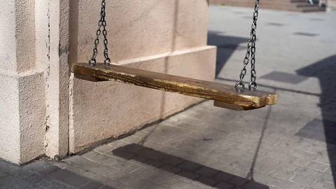 A nostalgic empty swing sways against a light wall Stock Footage 129754243