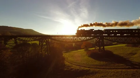 Nostalgic Historical Steam Engine Train Crossing Bridge at Sunset Light Stock Footage 168131712