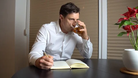 A nostalgic man writing a diary and drinking whiskey 스톡 동영상 123227707