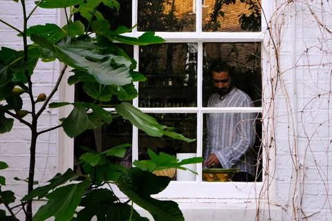 Nostalgic mid aged man looking down behind window Stock Photos