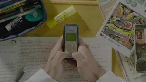 A nostalgic study desk scene featuring a classic Nokia 1100 phone, exam papers Video stock 302558024