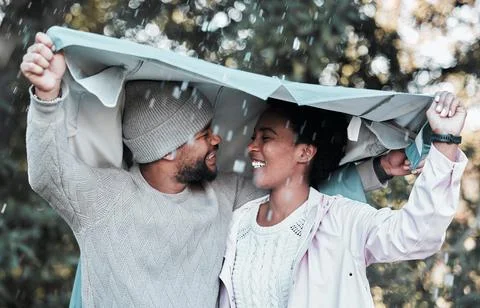 Not even the rain can keep me away from you. a young couple holding a jacket Fotos Stock