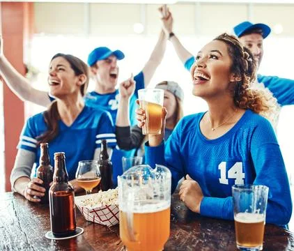 Not missing a minute of the action. a group of friends cheering while watching a Stock Photos