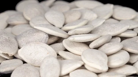 Not peeled pumpkin seeds close-up on a black background. Pumpkin seeds rotate Video stock 117724595