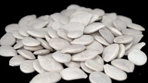 Not peeled pumpkin seeds close-up on a black background. Pumpkin seeds rotate Video stock 117724600