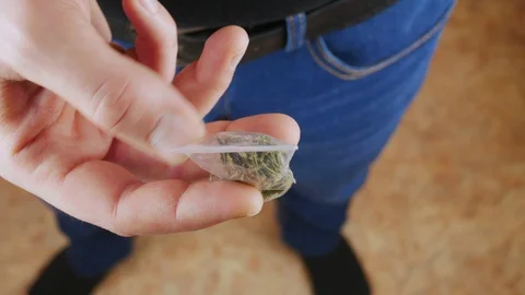 Not recognizable the man turns in his hands a small bag filled with marijuana. Stock Footage 128290359