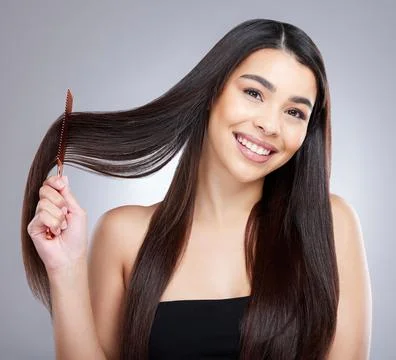 Not a tangle in sight. Studio portrait of an attractive young woman combing her Stock Photos