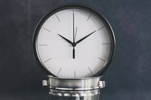 Not wasting time, oversize clock with miniature garbage bin on business desk Stock Photos