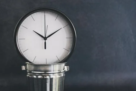 Not wasting time, oversize clock with miniature garbage bin on business desk Stock Photos