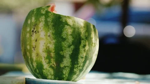 The notched watermelon lies on the table in the country house. Shadows from the Stock Footage