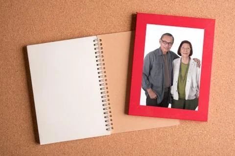 Note book and frame with picture of senior couples on wooden table Stock Photos