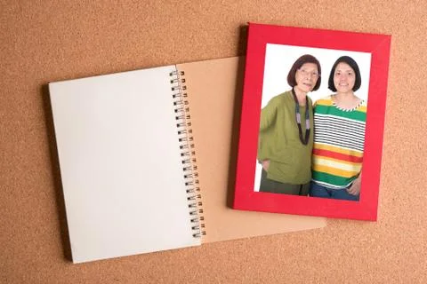 Note book and  frame with picture of mom and daughter on wooden table Stock Photos